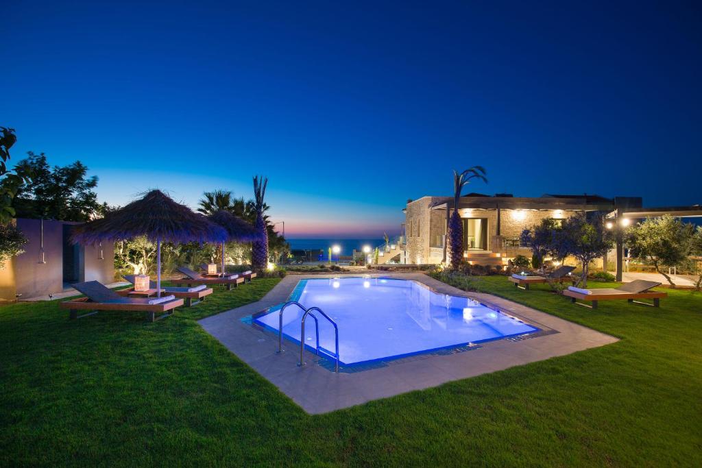 una piscina en un patio por la noche en Velvet Breeze Superior Villa, en Stavromenos