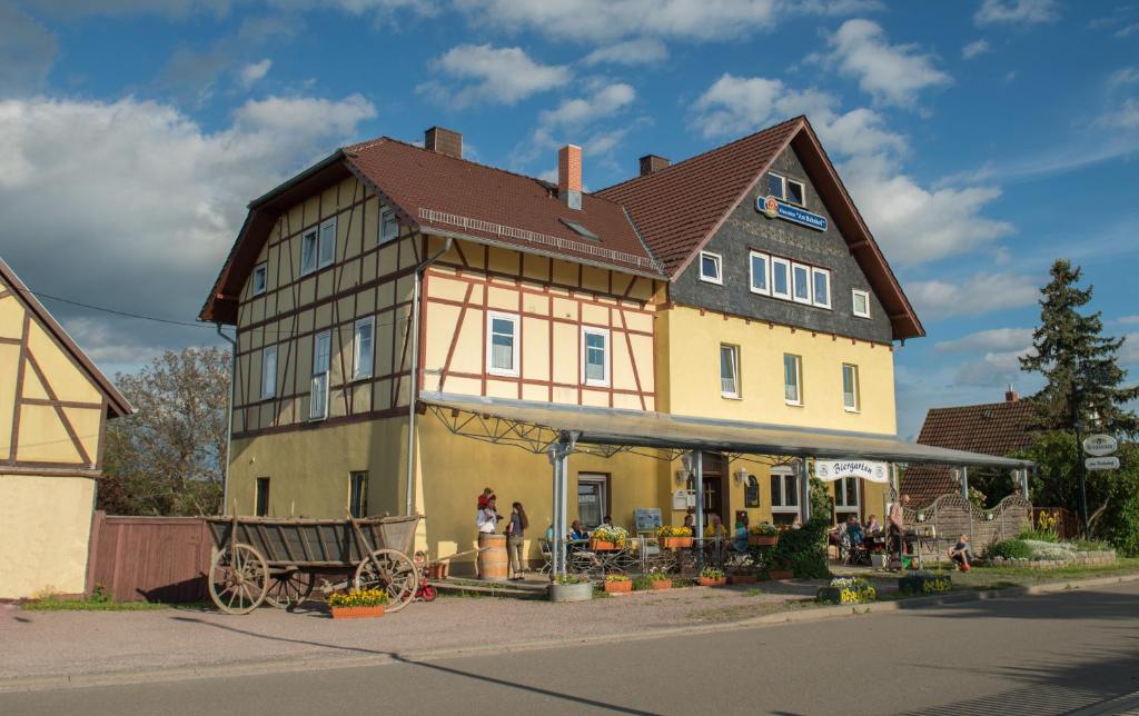 une grande maison avec un cheval et une calèche dans une rue dans l'établissement Landgasthof Marlishausen, à Arnstadt