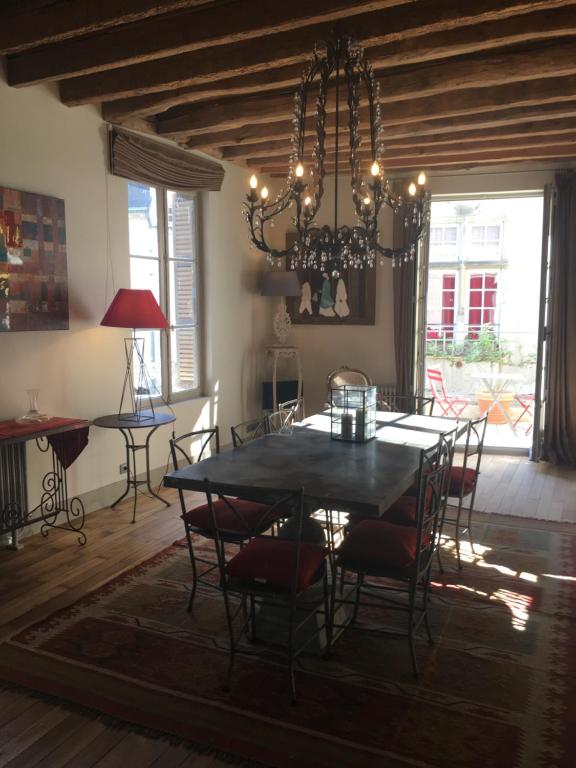 una sala da pranzo con tavolo, sedie e lampadario pendente di Maison Joséphine avec garage privé a Blois