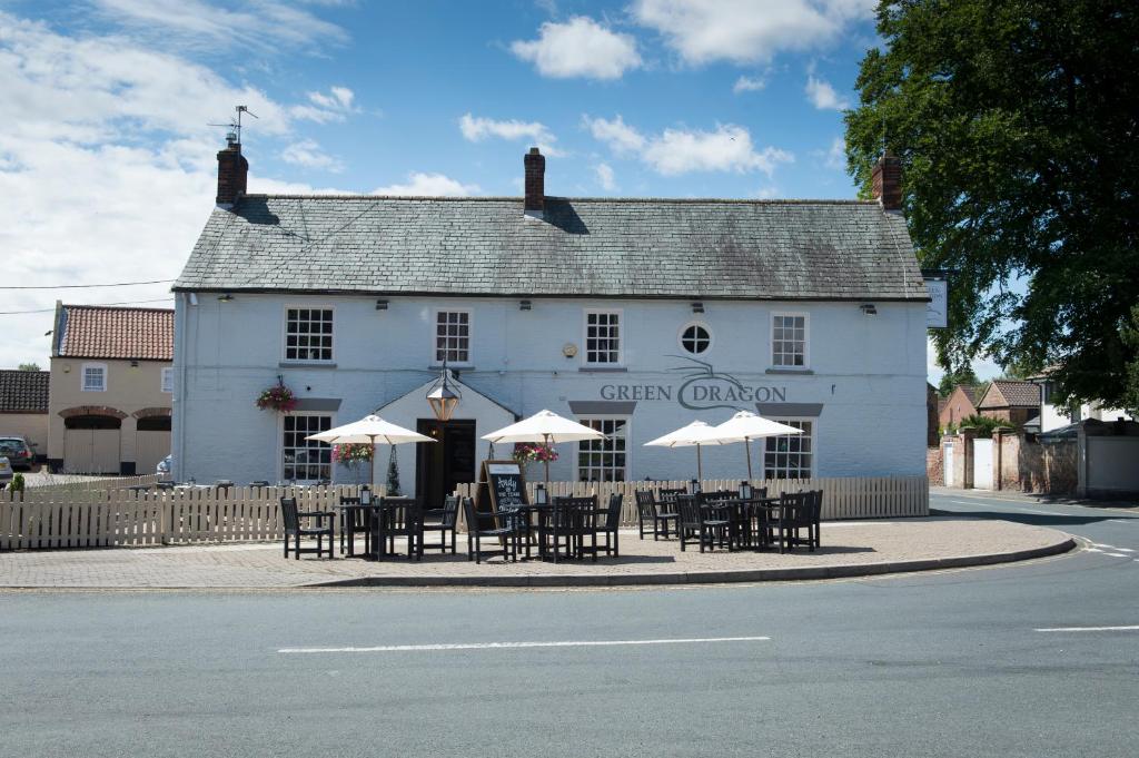 ein weißes Gebäude mit Tischen und Sonnenschirmen davor in der Unterkunft Green Dragon, Welton by Marston's Inns in South Cave