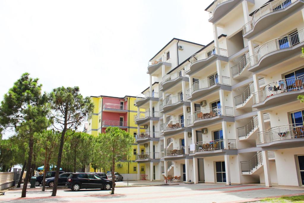 a large apartment building with cars parked in front of it at Residence Kullat in Velipojë