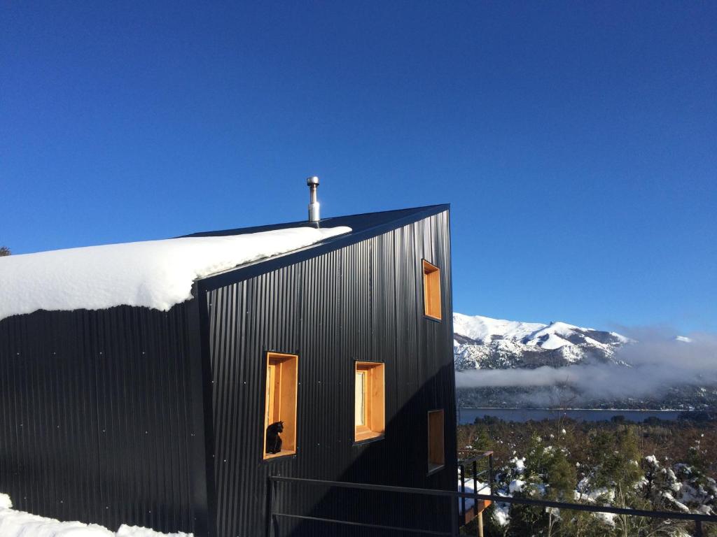 una casa negra con nieve encima en La melliza en San Carlos de Bariloche
