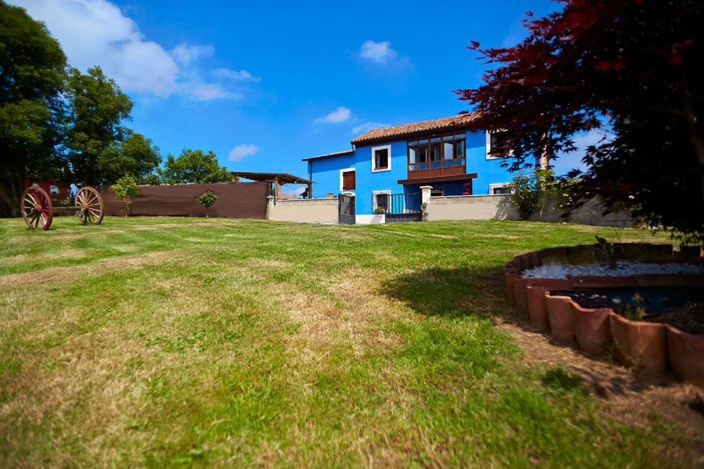 um grande quintal com uma casa azul ao fundo em La Piñera em Siero