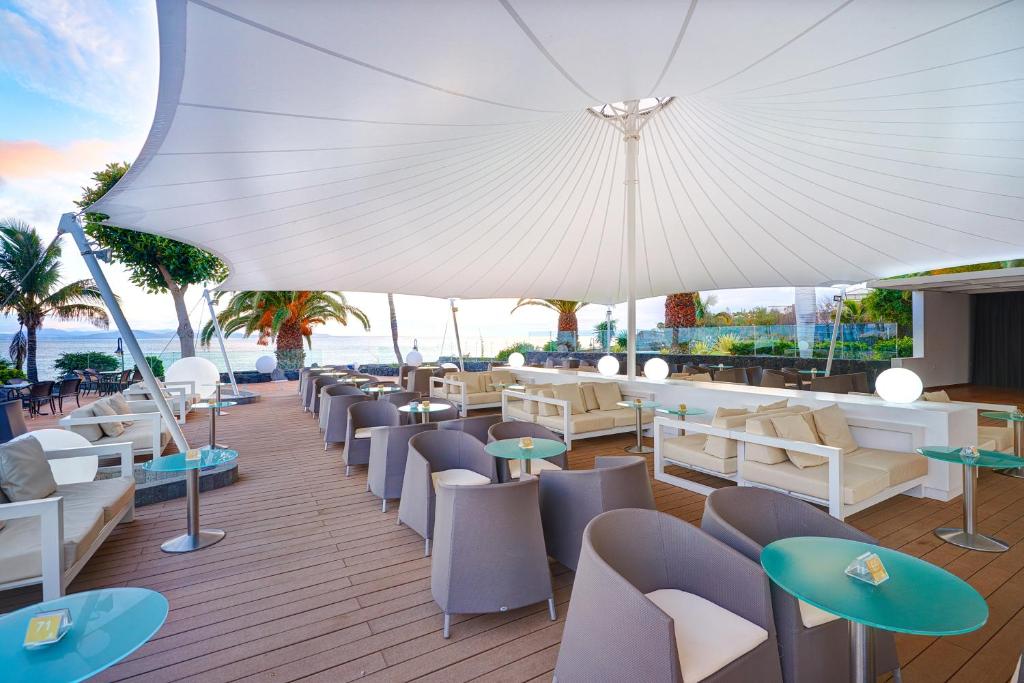 a restaurant with chairs and tables and an umbrella at Hipotels Natura Palace Adults Only in Playa Blanca