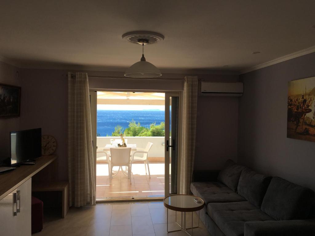 a living room with a couch and a view of the ocean at Augustus Hotel in Dhërmi