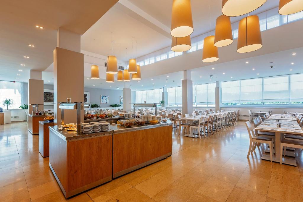 a restaurant with tables and chairs and a buffet at Hotel Zorna Plava Laguna in Poreč