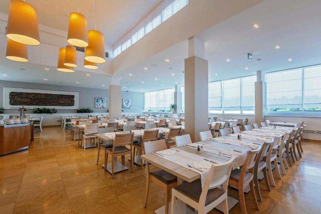 a dining room with long tables and chairs at Hotel Zorna Plava Laguna in Poreč