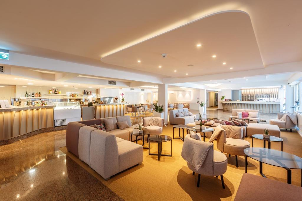 a hotel lobby with couches and tables and a kitchen at Hotel Zorna Plava Laguna in Poreč