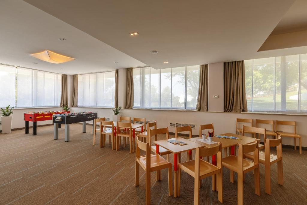 a restaurant with tables and chairs and a pool table at Hotel Zorna Plava Laguna in Poreč