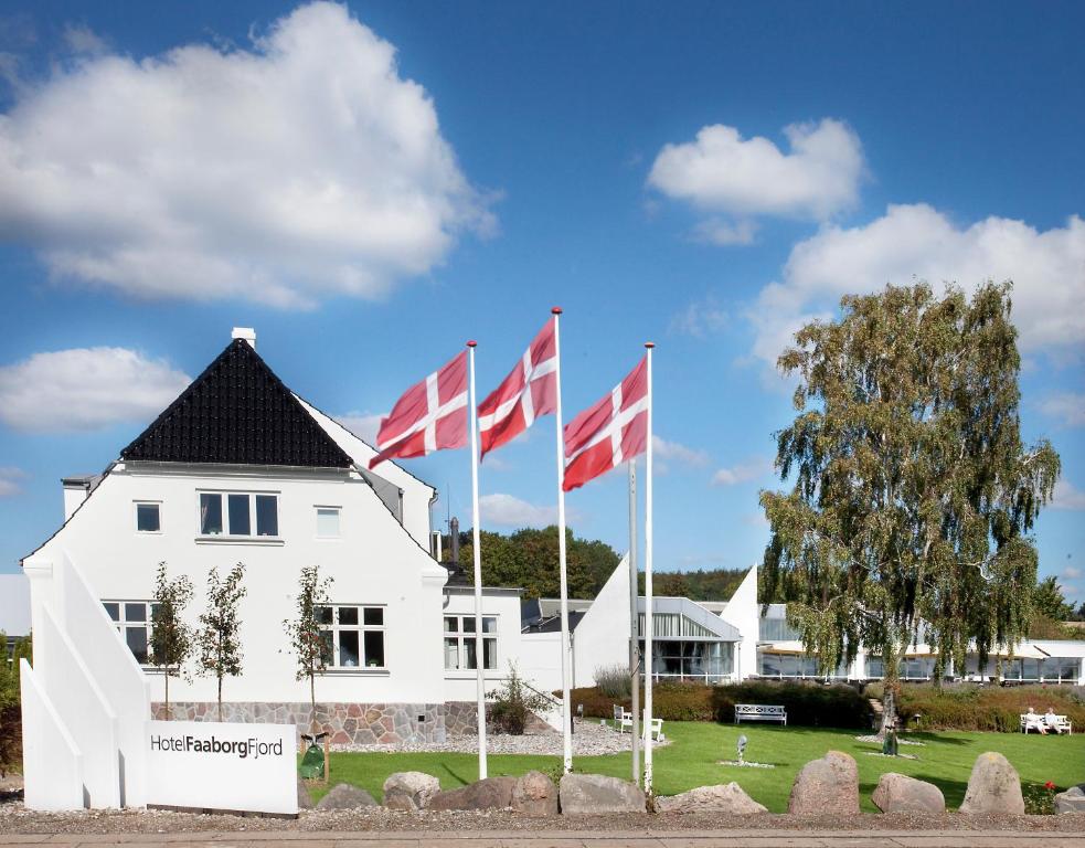 a white building with four canadian flags in front of it at Hotel Faaborg Fjord in Faaborg