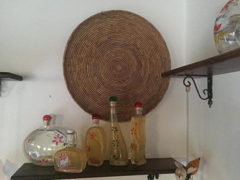 una mensola con bottiglie e un cesto appeso al muro di Agriturismo Vintura ad Aggius