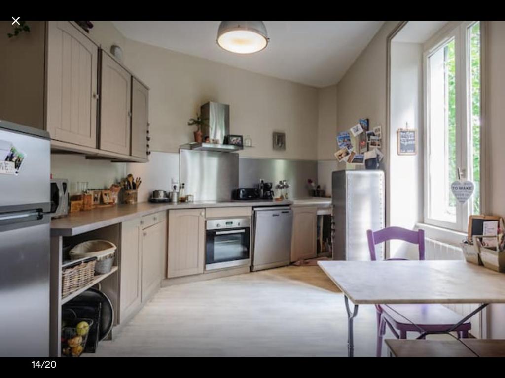 cocina con electrodomésticos de acero inoxidable y mesa en Maison de charme 1930 proche Lyon en Lentilly