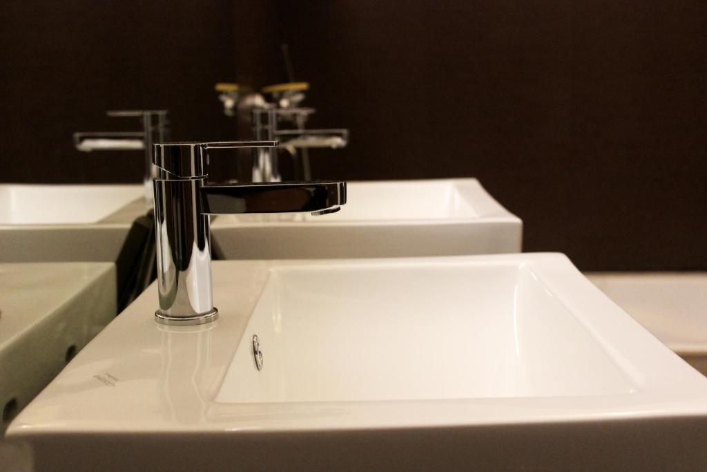 a white sink in a bathroom with two faucets at Hotel Grand Tizu in Dimāpur