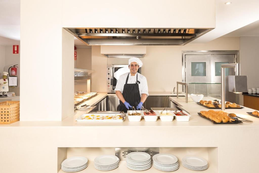 a chef standing in a kitchen with some food at Hotel Marsol in Lloret de Mar