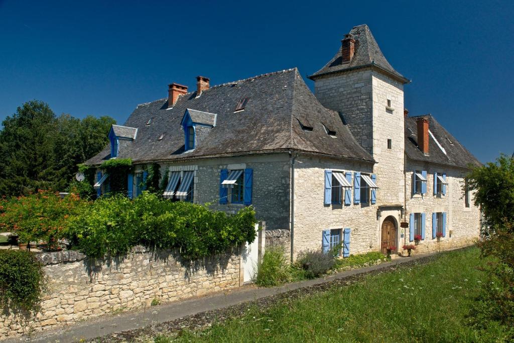 uma velha casa de pedra com uma chaminé em cima em Le Prieuré em Souillac