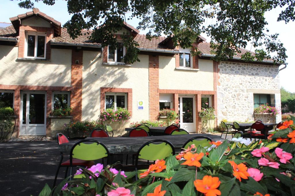 una casa con sillas y flores delante de ella en Auberge de la Normandie, en Junhac