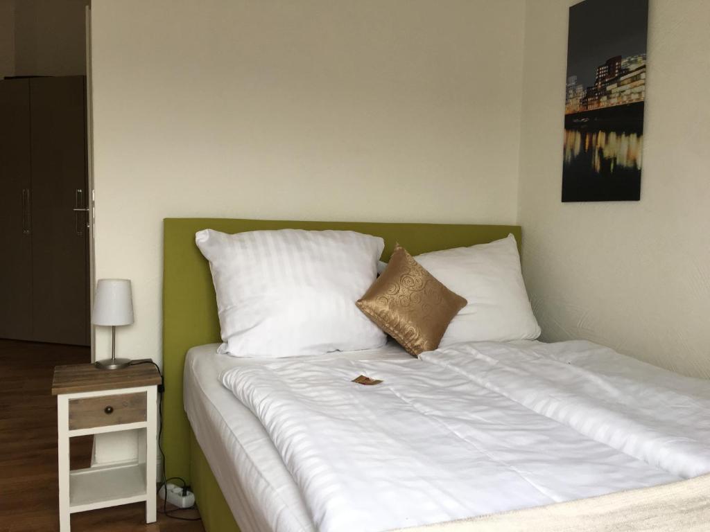 a bedroom with a bed with white pillows and a night stand at Studiotel Belle Etage in Düsseldorf