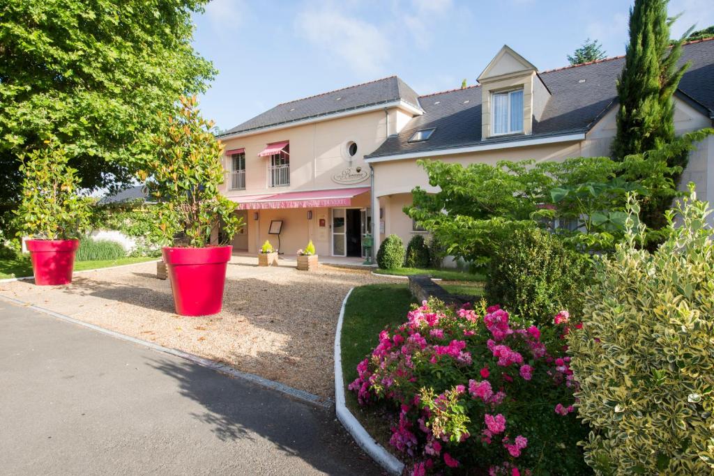 a house with red buckets in a yard with flowers at Logis Auberge Bienvenue in Doué-la-Fontaine