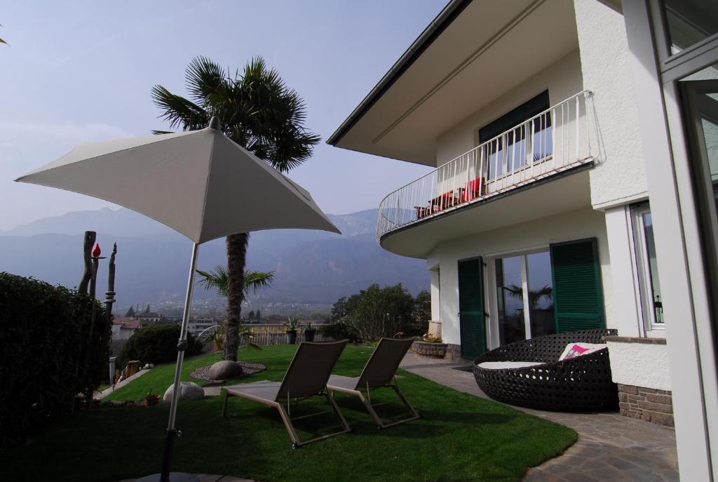- une terrasse avec 2 chaises et un parasol en face d'une maison dans l'établissement Torilan, à Terlano