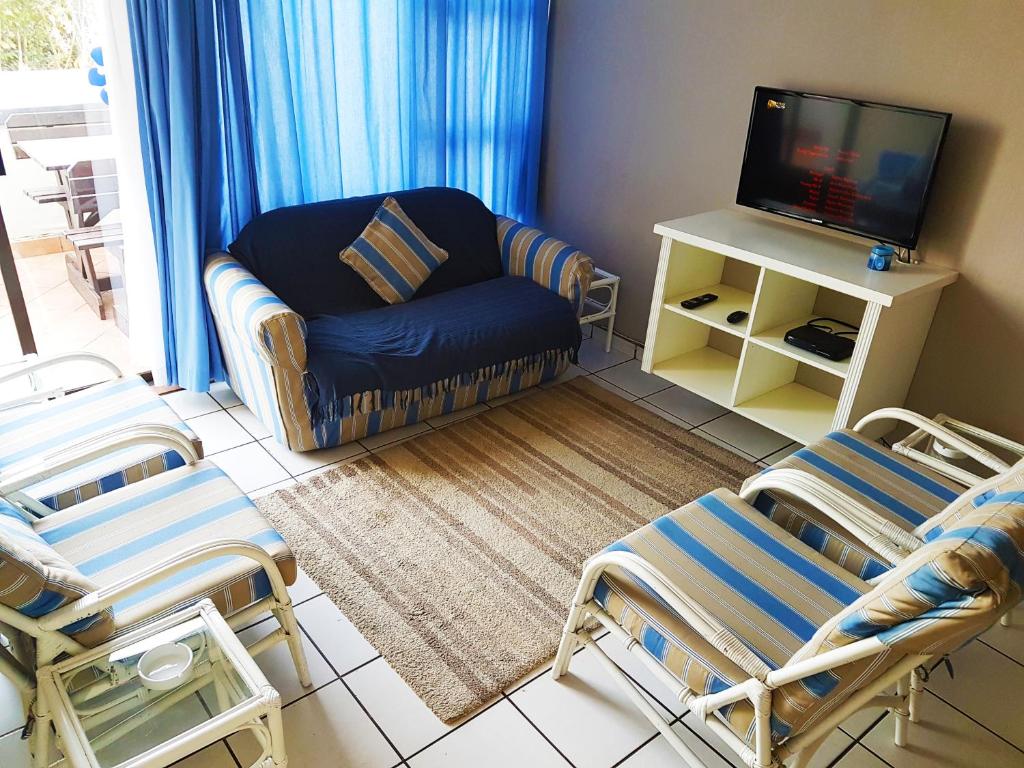 sala de estar con sofá, sillas y TV en Dumela Margate Flat No 3, en Margate