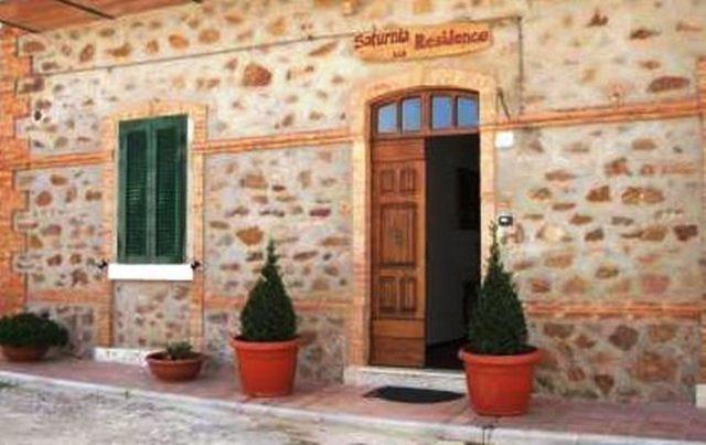 um edifício com uma porta de madeira e dois vasos de plantas em Saturnia Residence em Poggio Murella