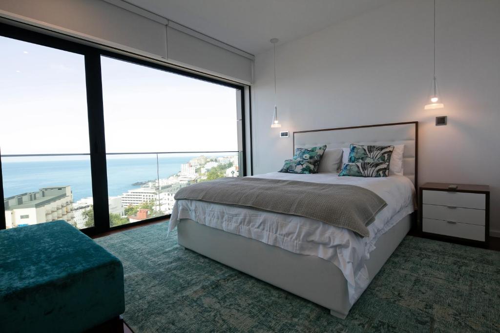 um quarto com uma cama grande e janelas grandes em Spacious luxury holiday apartment with a great view, Funchal, free wifi and parking no Funchal