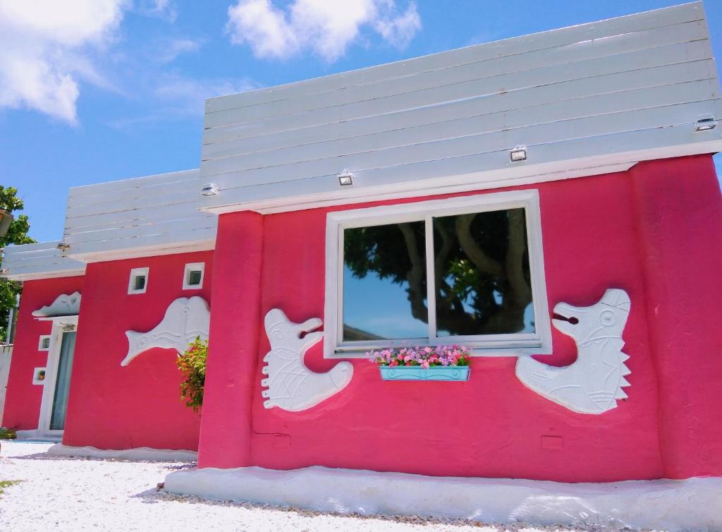 a pink building with a window with white cats painted on it at 灣境海邊小屋 in Eluan