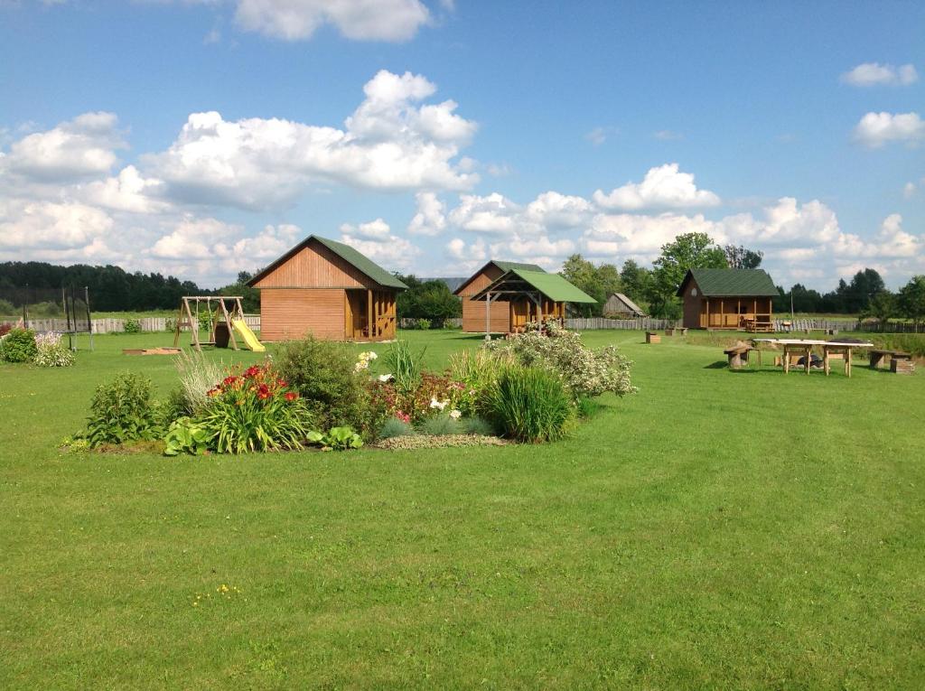 een tuin met huizen en een park met een speeltuin bij Ežmalas in Rembate