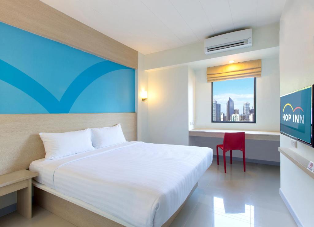 een slaapkamer met een wit bed en een rode stoel bij Hop Inn Hotel Makati Avenue Manila in Manilla