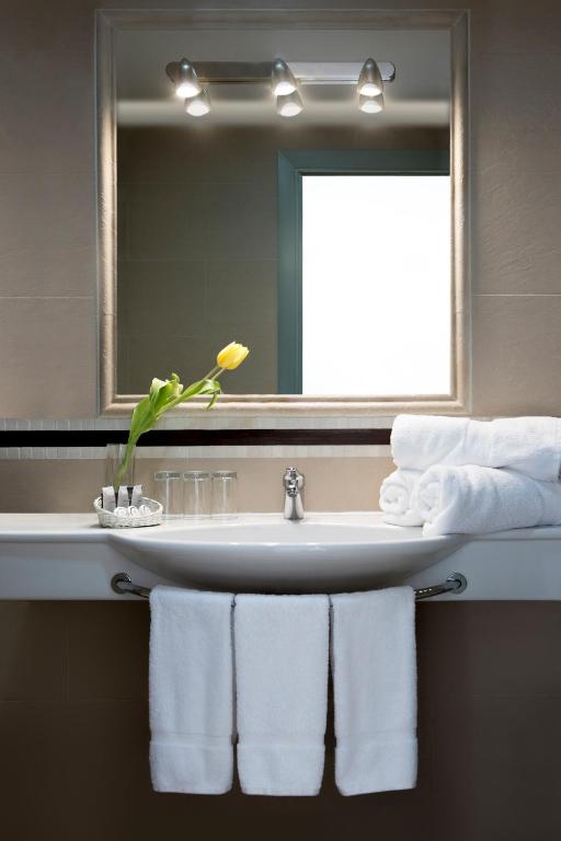 a bathroom with a sink and a mirror and towels at Hotel Plaza Cavana in Nerja