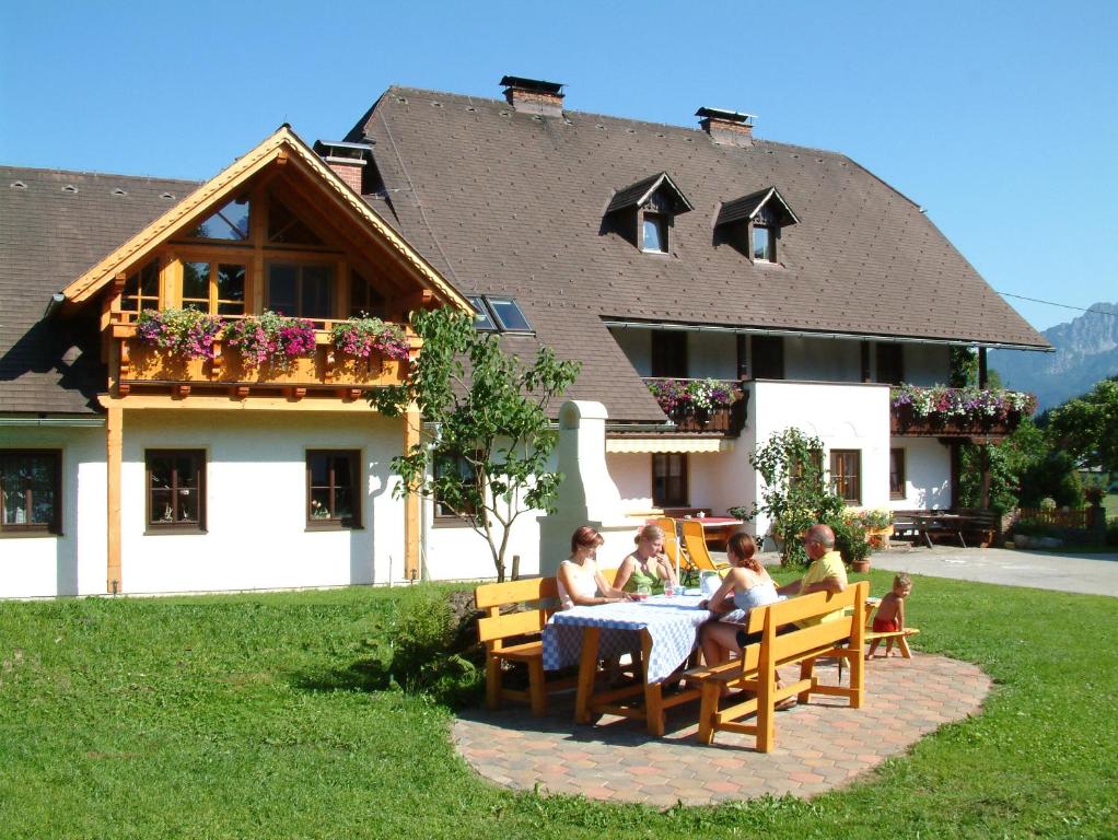 um grupo de pessoas sentadas numa mesa em frente a uma casa em Ferienhof Karin und Florian Gressenbauer em Edlbach