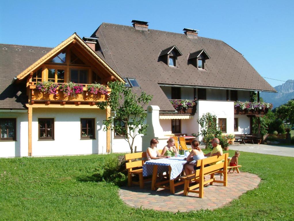 a group of people sitting at a table in front of a house at Ferienhof Karin und Florian Gressenbauer in Edlbach