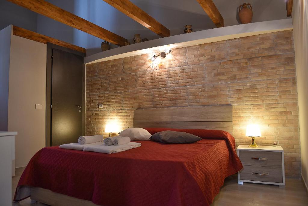 1 dormitorio con cama roja y pared de ladrillo en Famigi en Nápoles