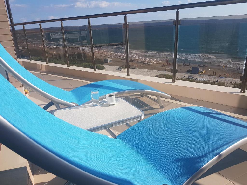 a balcony with blue chairs and a table and the ocean at Apart Hotel Iglika in Pomorie