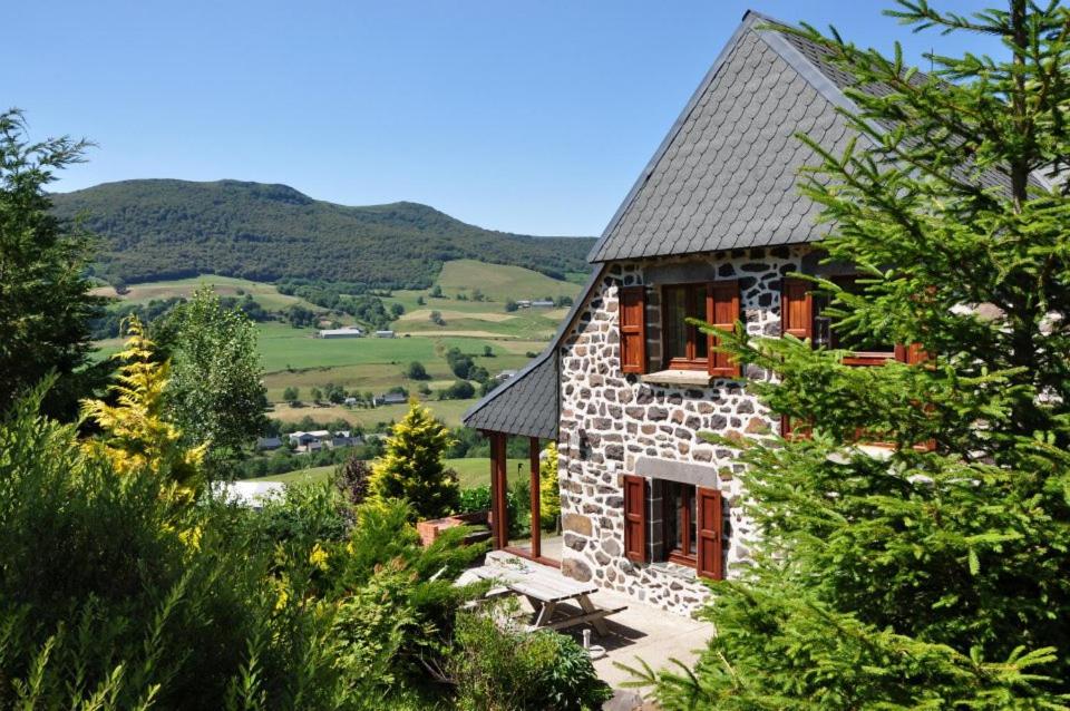 een stenen huis met een bankje ervoor bij Farmhouse with mountain view in Le Claux