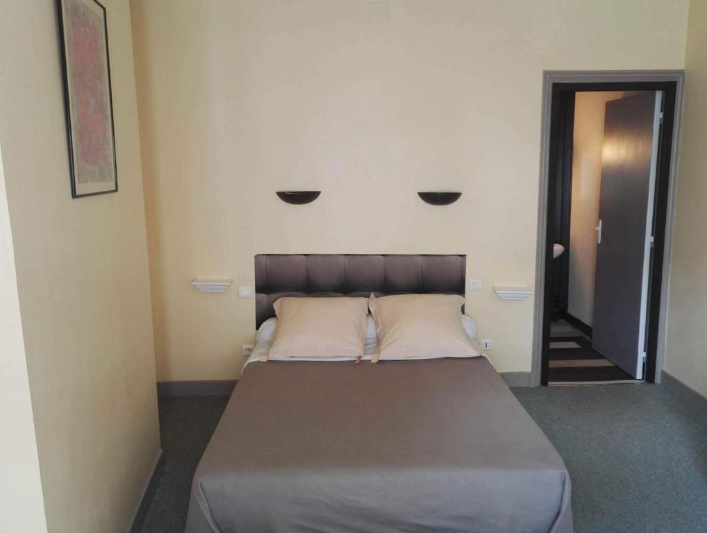 a bed in a room with two lights on the wall at Hotel Du Square in Riom