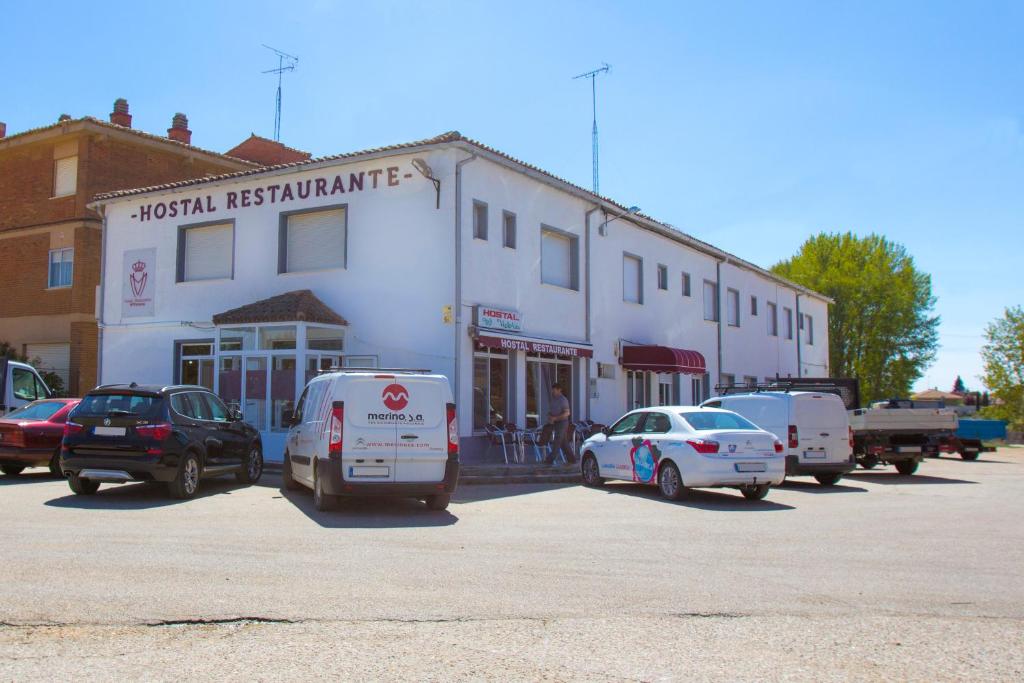 un gruppo di auto parcheggiate di fronte a un edificio di Hostal Restaurante María Victoria a La Mudarra