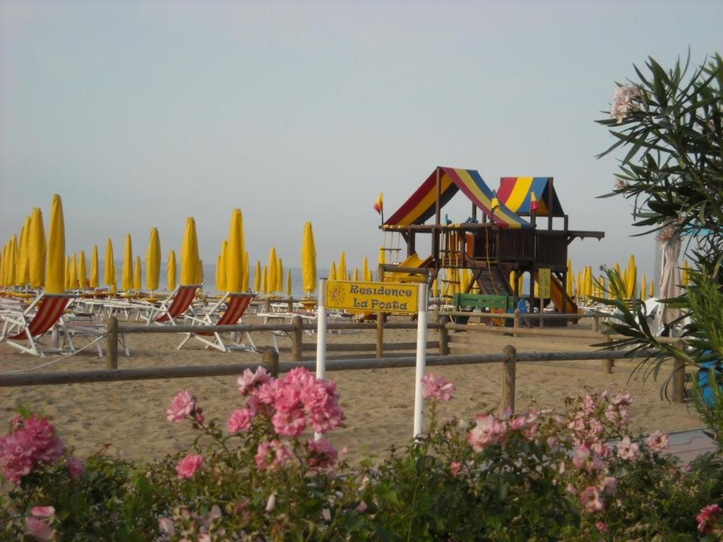 einen Strand mit Spielplatz, Stühlen und Sonnenschirmen in der Unterkunft B&C Apartments LA POSTA Home in Lido di Jesolo