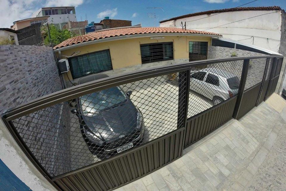 a fence with a car parked in a parking lot at Paraíso Olindense in Olinda