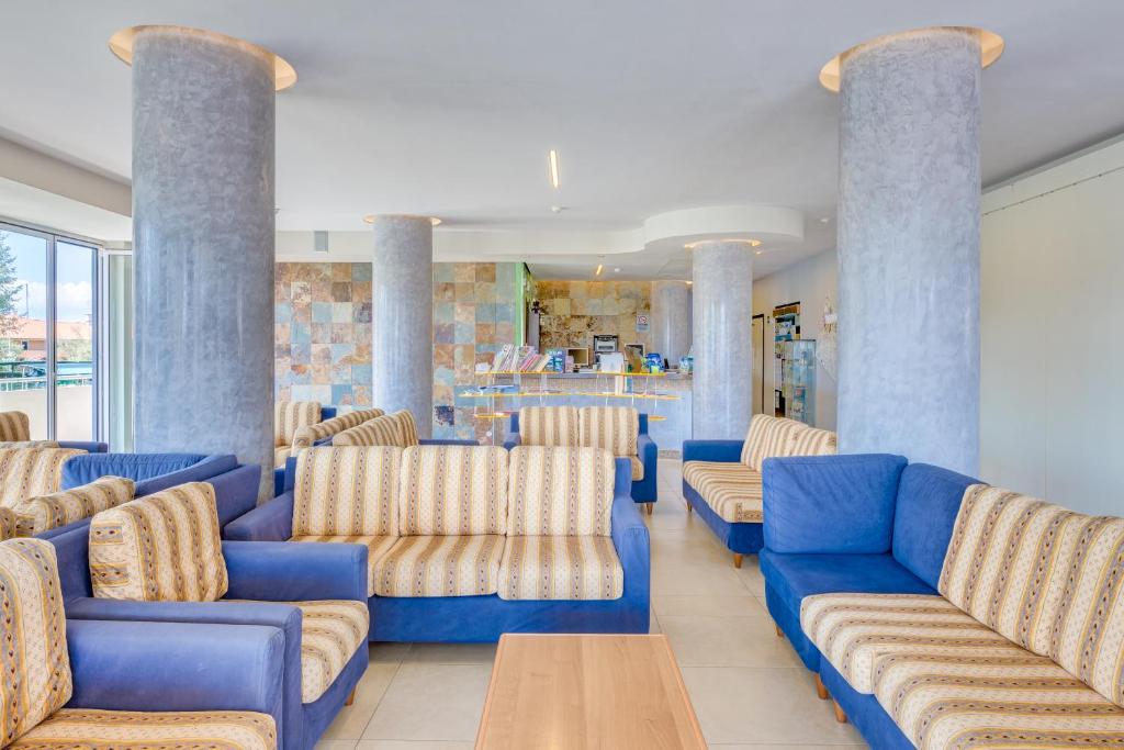 a waiting room with blue couches and a table at Hotel Ambassador in Caorle