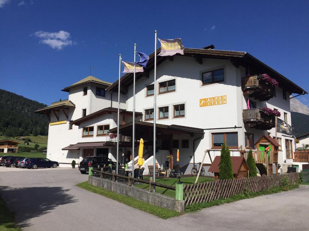 duży biały budynek z flagami przed nim w obiekcie Alpenstern Pension Suites w mieście Lermoos