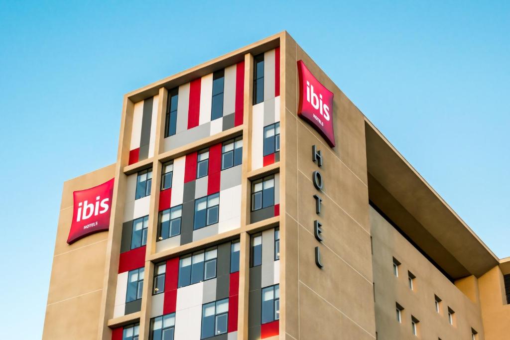 a tall building with the ibis sign on it at ibis Copiapo in Copiapó