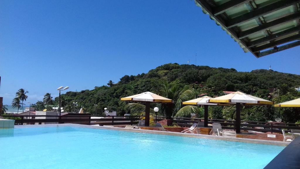 a large swimming pool with umbrellas and chairs at Imo Apart Pipa's Ocean in Pipa