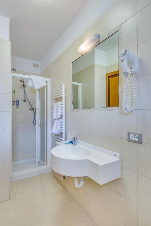 a white bathroom with a sink and a shower at Hotel Ambassador in Caorle
