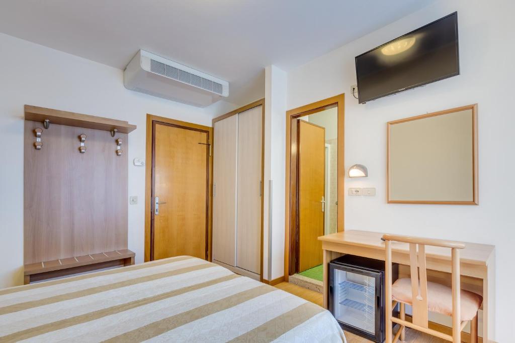 a bedroom with a bed and a desk and a table at Hotel Ambassador in Caorle