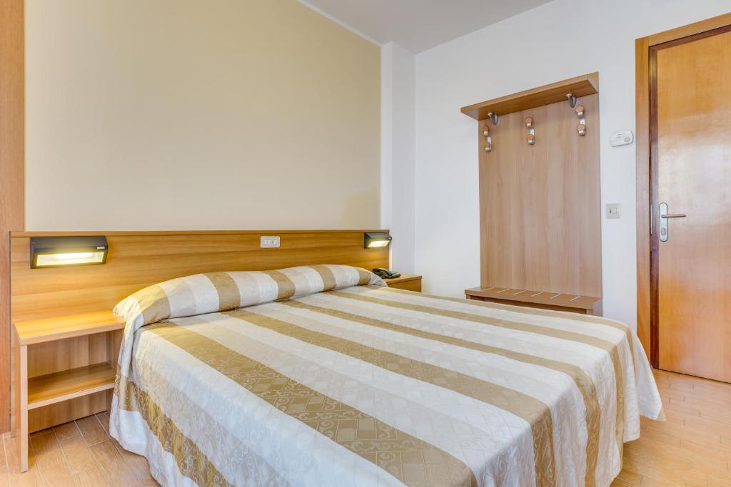a bedroom with a large bed with a wooden headboard at Hotel Ambassador in Caorle