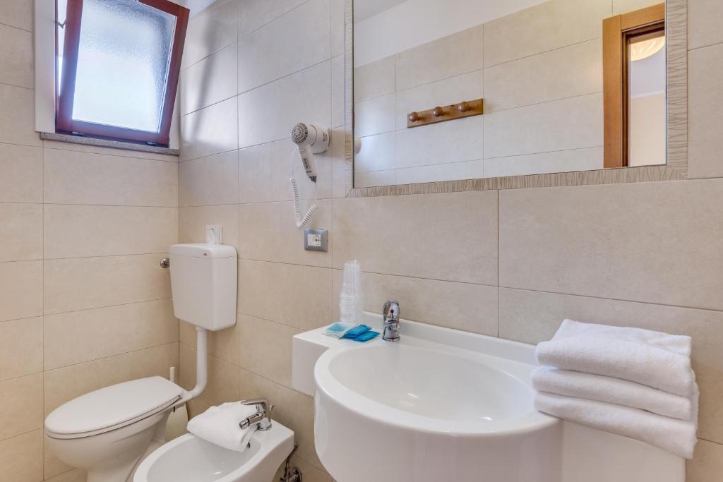 a bathroom with a white toilet and a sink at Hotel Ambassador in Caorle