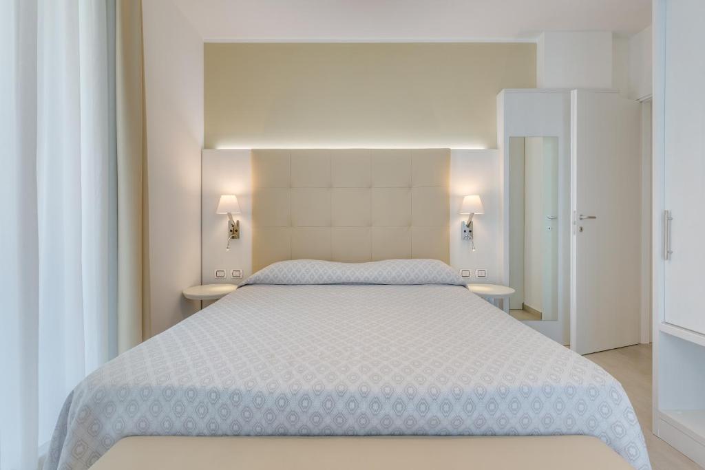 a bedroom with a large white bed with two tables at Hotel Ambassador in Caorle