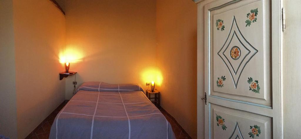 CaninoにあるAgriturismo Terre di Musignanoのベッド1台(壁に照明2つ付)が備わる小さな客室です。