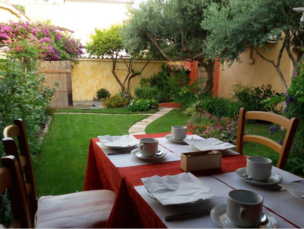 una mesa con un mantel rojo y tazas en ella en B&B Dimora Degli Ulivi, en Muravera